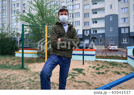teen boy stands by seesaw on playground near teen boy stands by seesaw on playground near 65043537
