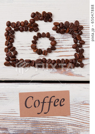 Coffee beans on the table arranged in a shape of photo camera. Coffee beans on the table arranged in a shape of photo camera. 65047888