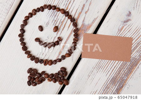 Coffee beans arranged in a happy smiley with bow tie. Coffee beans arranged in a happy smiley with bow tie. 65047918