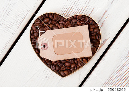Heart shaped coffee beans with blank paper tag. 65048266