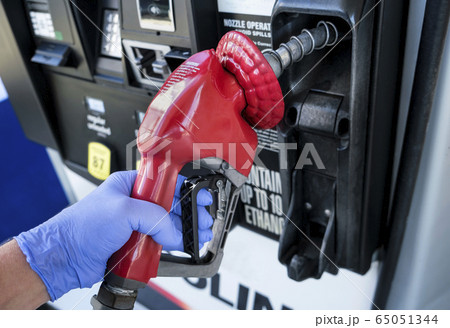 Gloved hand holding gas station nozzle Gloved hand holding gas station nozzle 65051344