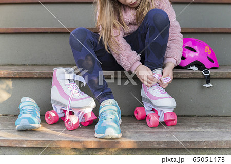 Girl tying the laces of her roller skates 65051473