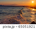鵠沼海岸から眺める太陽が沈みかける夕暮れの海岸線の美しい波しぶきと富士山、サーファー 65051921