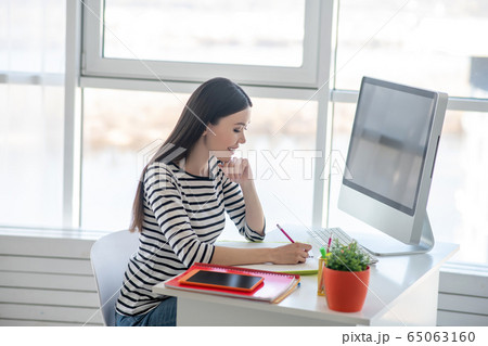 Dark-haired pretty woman in a striped shirt looking busy Dark-haired pretty woman in a striped shirt looking busy 65063160