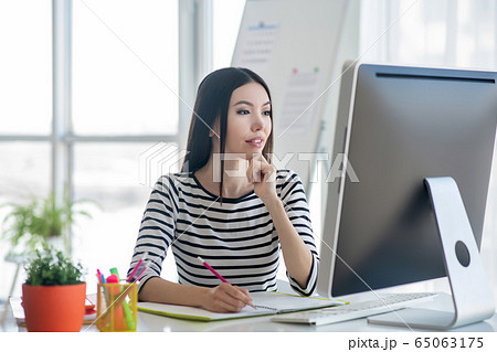 Dark-haired pretty woman in a striped shirt looking serious Dark-haired pretty woman in a striped shirt looking serious 65063175