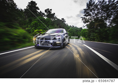 Blue sedan driving across natural rain forests under the sunlight Blue sedan driving across natural rain forests under the sunlight 65064787