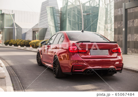 Red model sedan on the empty city roads, view from behind Red model sedan on the empty city roads, view from behind 65067484