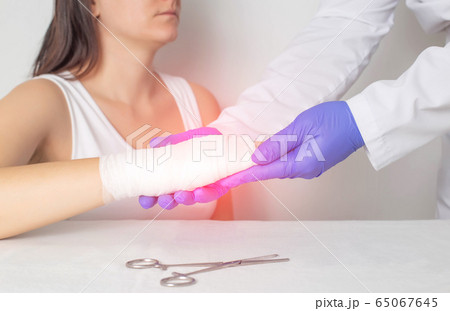 A surgeon doctor examines a patient s palm for a fracture or crack in a bone. Scaphoid fracture, red A surgeon doctor examines a patient s palm for a fracture or crack in a bone. Scaphoid fracture, red 65067645