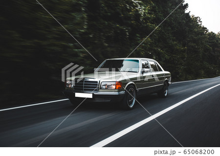 Vintage silver sedan driving in the forest in the evening ,commercial photoshooting 65068200