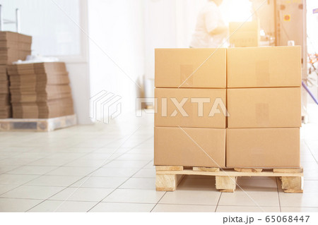 Boxes on a pallet with finished products of sunflower oil on the background of a production workshop with equipment, copy space, business 65068447