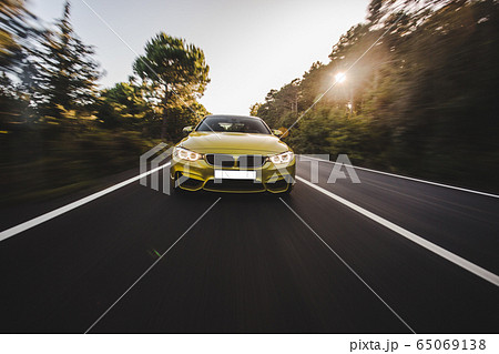 Yellow luxury sedan speed drive in the countryside in the sunset Yellow luxury sedan speed drive in the countryside in the sunset 65069138