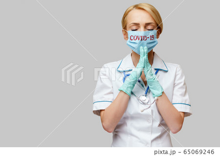 medical doctor nurse woman wearing protective mask and latex gloves - praying nad hoping gesture 65069246