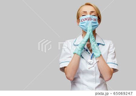 medical doctor nurse woman wearing protective mask and latex gloves - praying nad hoping gesture 65069247