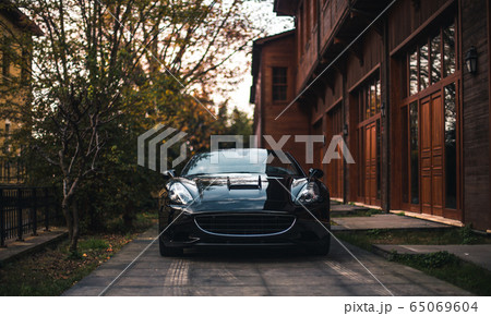 Black sedan car in the yard of a building,under the trees Black sedan car in the yard of a building,under the trees 65069604