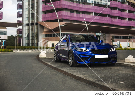 Blue sport model sedan touring in the megapolis, red building behind Blue sport model sedan touring in the megapolis, red building behind 65069701