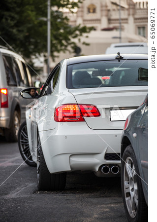 White sedan driving on the central road, waiting in the traffic lights,view from behind 65069771