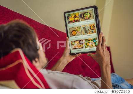 man orders food for lunch online using Tablet man orders food for lunch online using Tablet 65072160