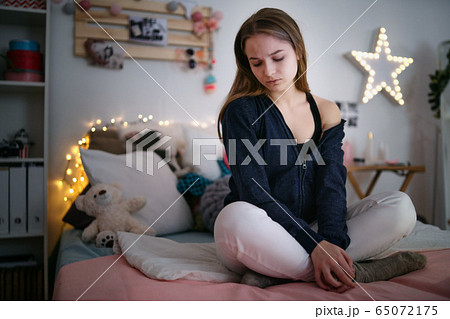 Worried young girl sitting indoors on bed, online dating concept. Worried young girl sitting indoors on bed, online dating concept. 65072175