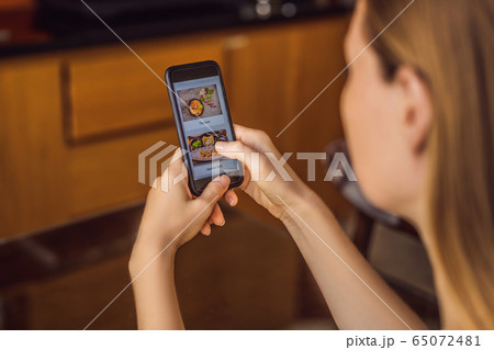 Young woman orders food for lunch online using a smartphone Young woman orders food for lunch online using a smartphone 65072481