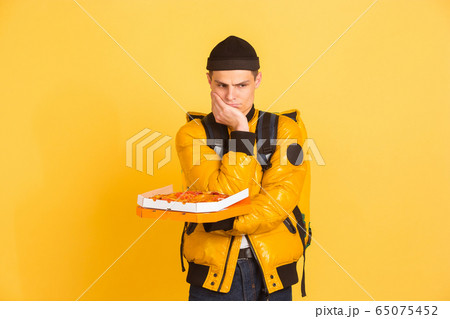 Contacless delivery service during quarantine. Man delivers food and shopping bags during insulation. Emotions of deliveryman isolated on yellow background. 65075452
