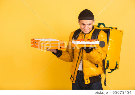 Contacless delivery service during quarantine. Man delivers food and shopping bags during insulation. Emotions of deliveryman isolated on yellow background. Contacless delivery service during quarantine. Man delivers food and shopping bags during insulation. Emotions of deliveryman isolated on yellow background. 65075454
