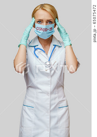 medical doctor nurse woman wearing protective mask and rubber or latex gloves - headache and stress 65075472