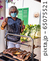 elderly lady cooking on a barbecue with face mask 65075521