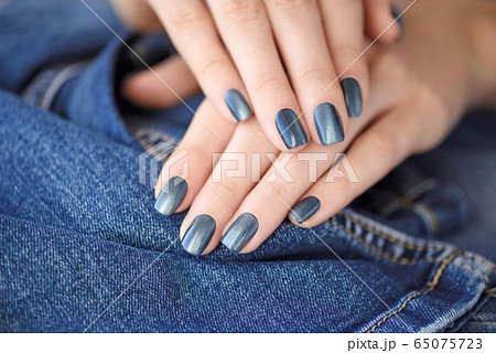Hands with dark blue manicured nails on jeans 65075723