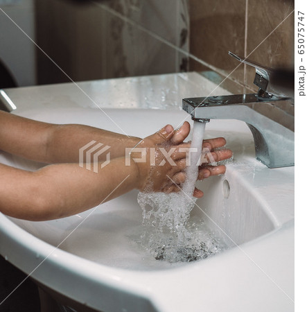 The kid washes his hands with sanitizer 65075747