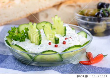 Fresh Greek tzatziki with garlic and cucumber, flat bread and olives in the background Fresh Greek tzatziki with garlic and cucumber, flat bread and olives in the background 65076631
