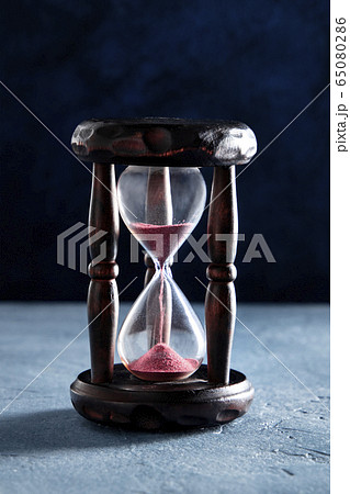 Time concept. An hourglass with flowing sand, time flies Time concept. An hourglass with flowing sand, time flies 65080286