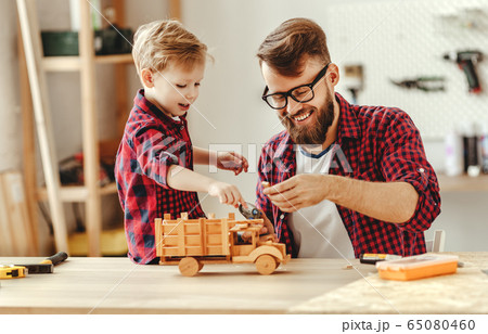 Cheerful man with kid making wooden toys in 65080460