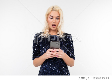 pensive lady in a shiny dress surfing the Internet from the phone on a white background with copy 65081914