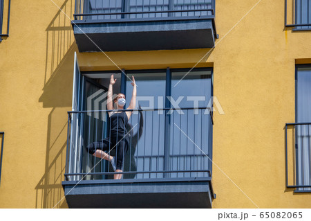 woman in mask practices yoga on balcony of the apartment. Stay home 65082065