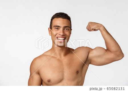 African American teenager shows muscles on arm. Isolated on white background. Studio portrait. Transitional age concept. African American teenager shows muscles on arm. Isolated on white background. Studio portrait. Transitional age concept. 65082131