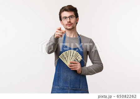 Small business, finance and career concept. Portrait of serious-looking young determined guy telling you secret how to earn money, become rich on your enterprise, hold cash and point camera 65082262