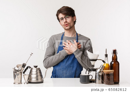 Barista, cafe worker and bartender concept. Portrait of touched handsome young male employee in apron making coffee, touch heart and feel flattered, customer likes his cappuccino Barista, cafe worker and bartender concept. Portrait of touched handsome young male employee in apron making coffee, touch heart and feel flattered, customer likes his cappuccino 65082612