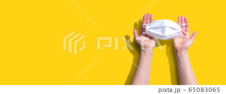 Person holding a white surgical mask overhead view 65083065
