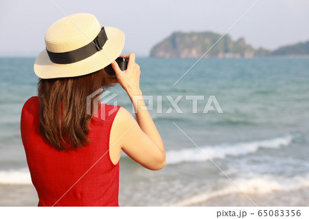 Woman taking photo on beach Woman taking photo on beach 65083356