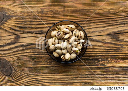 Pistachios in a small plate on a vintage wooden table as a background with a copy space. Pistachio is a healthy vegetarian protein nutritious food. Natural nuts snacks. Pistachios in a small plate on a vintage wooden table as a background with a copy space. Pistachio is a healthy vegetarian protein nutritious food. Natural nuts snacks. 65083703