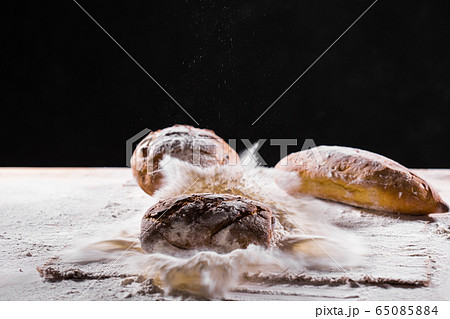 Traditional artisan rye bread loaf fall into flour. Dark background. Bakery and homemade rustic bread concept. 65085884