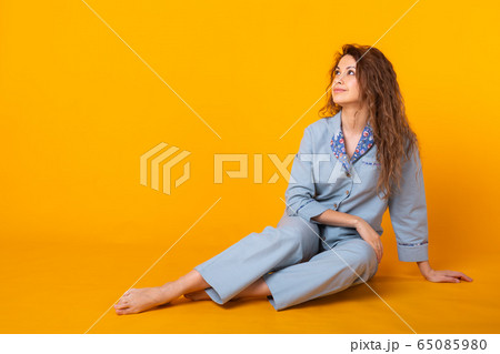 Close up young woman in blue home wear. Isolated on yellow background. Pajama concept. Close up young woman in blue home wear. Isolated on yellow background. Pajama concept. 65085980