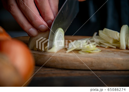 Slicing onion on cutting board in kitchen. 65086274