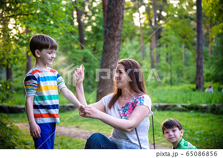 Young woman mother applying insect repellent to Young woman mother applying insect repellent to 65086856