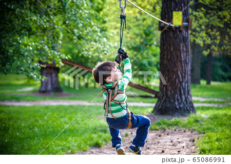 smiling boy rides a zip line. happy child on the smiling boy rides a zip line. happy child on the 65086991