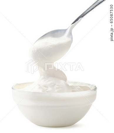 Sour cream flows from a spoon in a bowl on a white Sour cream flows from a spoon in a bowl on a white 65087530