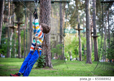smiling boy rides a zip line. happy child on the 65088902