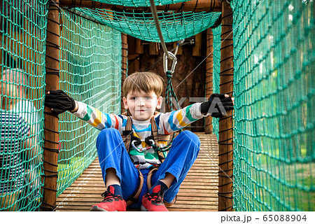 Cute boy overcomes obstacles in rope adventure Cute boy overcomes obstacles in rope adventure 65088904