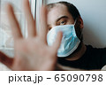 Coronavirus. Sick man of corona virus looking through the window and wearing mask protection. 65090798