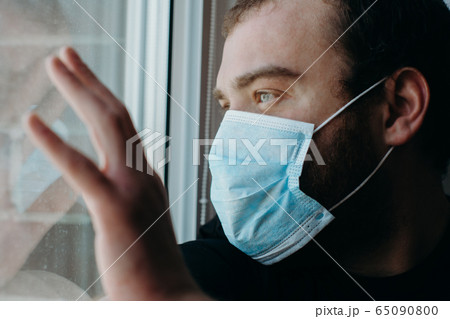 Coronavirus. Sick man of corona virus looking through the window and wearing mask protection. Coronavirus. Sick man of corona virus looking through the window and wearing mask protection. 65090800
